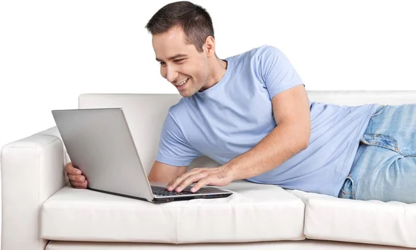 Homem relaxante no sofá com um laptop — Fotografia de Stock