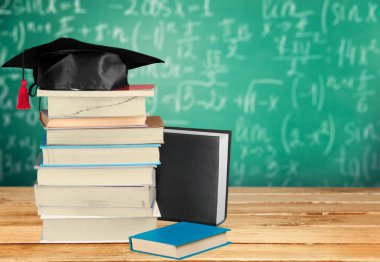 Mezuniyet şapka ve bulanık arka plan üzerinde kitap yığını 