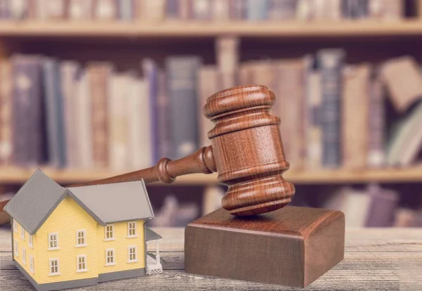 Wooden judge gavel and house on table