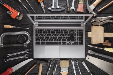 siyah ahşap masa arka plan üzerinde araçlarla yakın çekim gümüş dizüstü