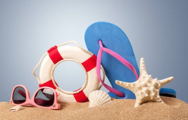 plaj aksesuarları kum üzerinde Close-Up. Parmak arası terlik, güneş gözlüğü, deniz yıldızları, havlu