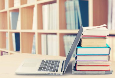 Dizüstü bilgisayar ile kitap yığını