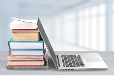 Masada dizüstü bilgisayar ile kitap yığını 
