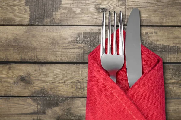 フォークとナイフは木製の背景に赤いナプキン — ストック写真
