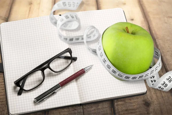 Notebook with measuring tape and an apple — Stock Photo, Image