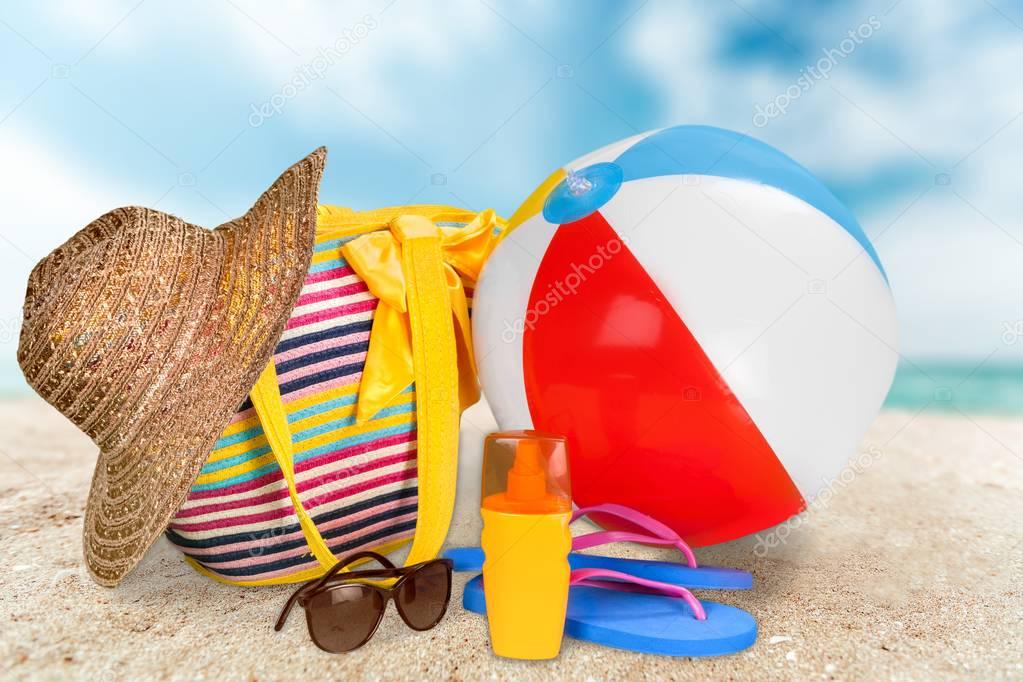 close-up of beach accessories on sand. Flip-flops, sunglasses, hat, towel, ball
