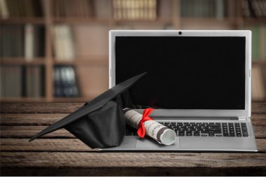 Dizüstü bilgisayar ve diploma kaydırma ve mezuniyet şapka 