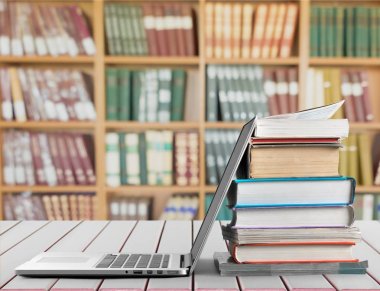 Dizüstü bilgisayar ile kitap yığını