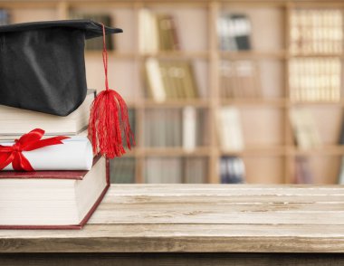 Graduation hat on stack of books clipart