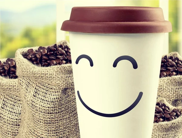 Coffee in paper cup with smile  on  background