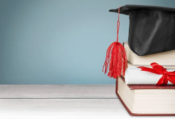 Avläggande av examen hatt på trave böcker — Stockfoto
