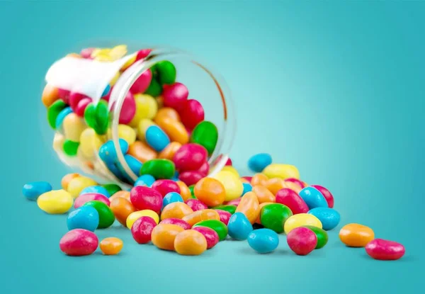 Kleurrijke snoepjes vallen uit een glazen pot — Stockfoto