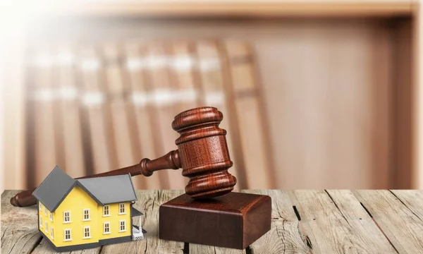 Wooden judge gavel and house on table