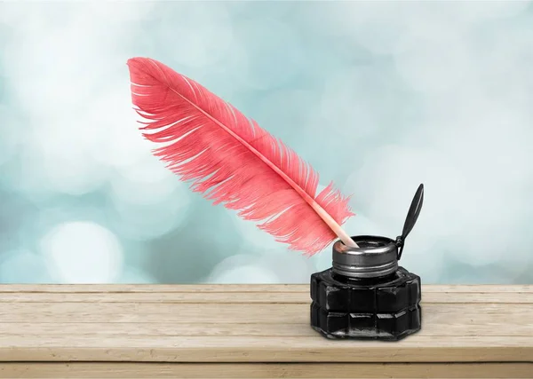 Feather quill pen and glass inkwell