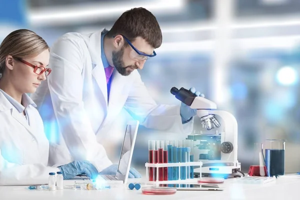 Mikroskopla çalışan erkek ve kadın bilim adamları