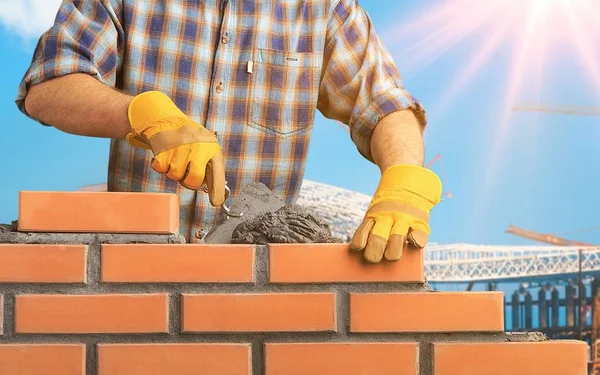 İşçi eve tuğla duvar örüyor.