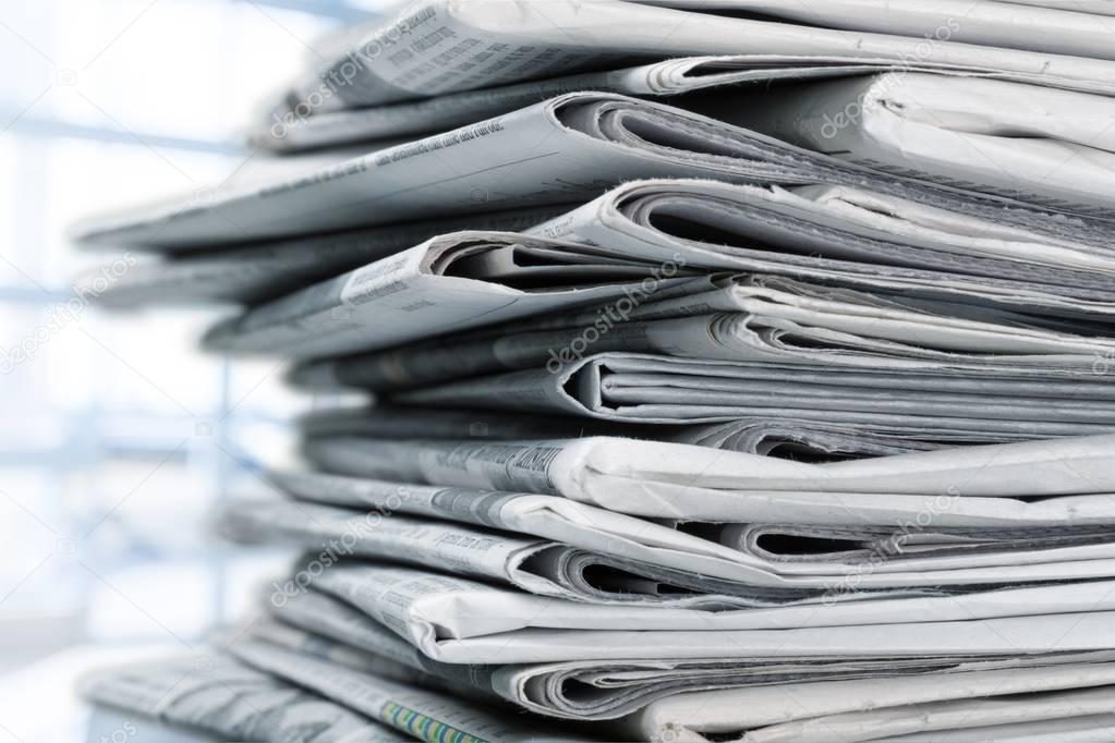 Pile of printed newspapers on white background