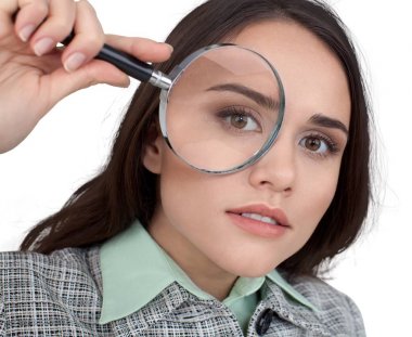 Beyaz arka plan üzerinde izole büyütme cam kullanarak takım elbiseli genç iş kadını 