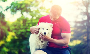 Yakışıklı delikanlı ile yeşil park arka plan üzerinde beyaz köpek