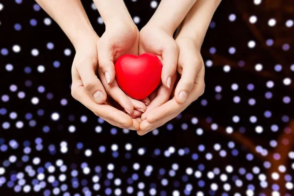 Hombre y mujer sosteniendo el corazón rojo — Foto de Stock