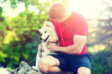 Yakışıklı delikanlı ile yeşil park arka plan üzerinde beyaz köpek