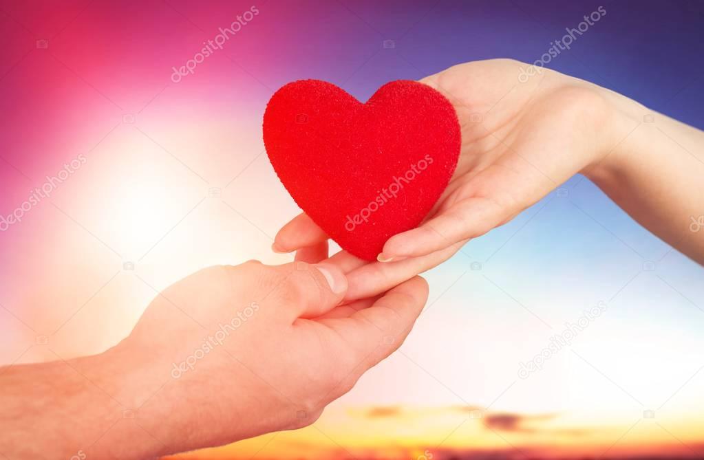 Red Heart in hands on background