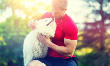 Yakışıklı delikanlı ile yeşil park arka plan üzerinde beyaz köpek