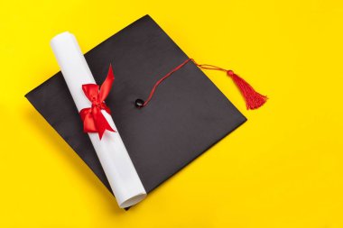 Mezuniyet şapka ve Sarı zemin üzerine diploma 