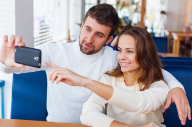 yakışıklı genç kadın kafe arka plan üzerinde telefon kullanarak moda giysileri ile