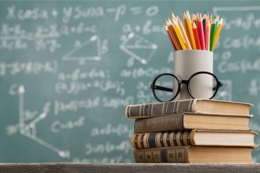  Tablo kalemleri ve gözlük ile kitap yığını