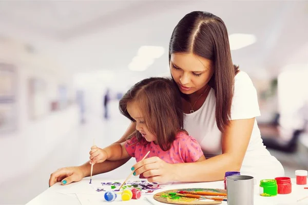 Young mother and her daughter painting together. Happy family