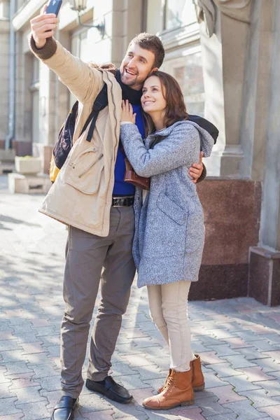 handsome man with young woman in fashion clothes take photo on city background