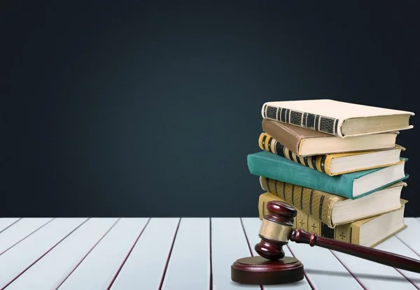 Ancient books in row and hammer on wooden table