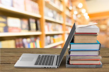 Masada dizüstü bilgisayar ile kitap yığını