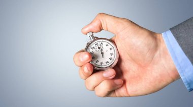 Gri arka plan üzerinde insan elinde kronometre