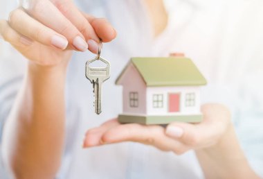 Küçük ev modeli ve anahtar tutan kadın