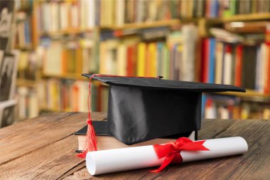 Mezuniyet şapka, kitap ve diploma masada 