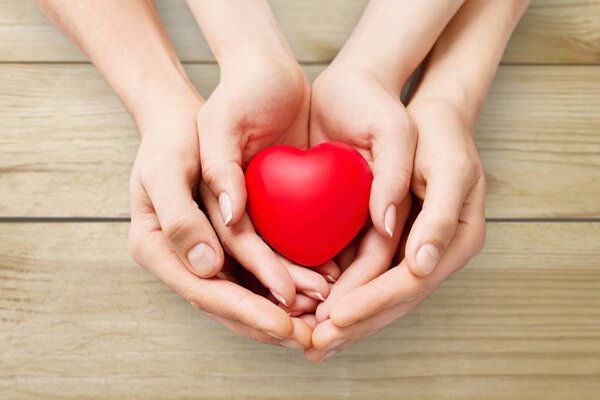 Man and woman holding red heart on  background 