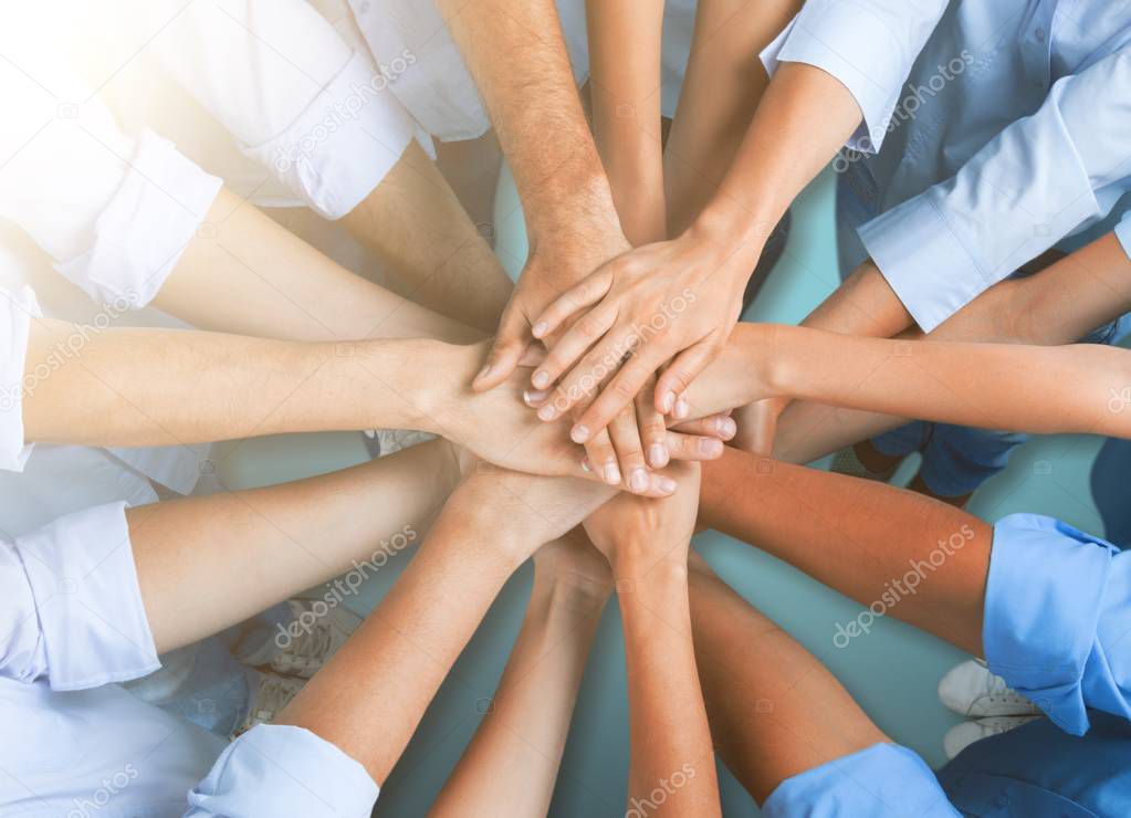 People stacking hands on light background 