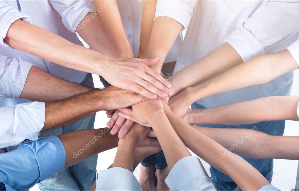 People stacking hands on light background 