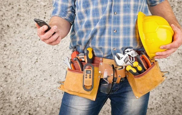 Young man worker with tool belt  and phone