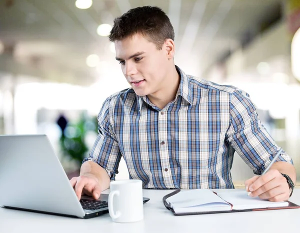 Jovem feliz trabalha em seu laptop — Fotografia de Stock