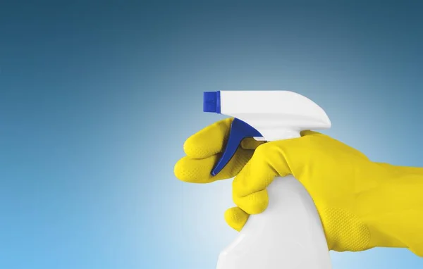 Hand in rubber glove holding spray bottle