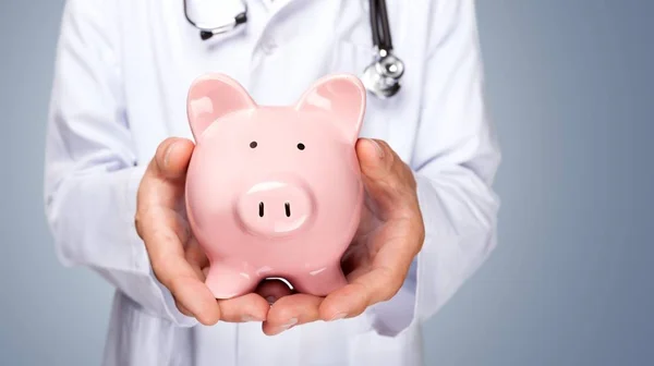 Médico com Estetoscópio Segurando Piggy Bank — Fotografia de Stock