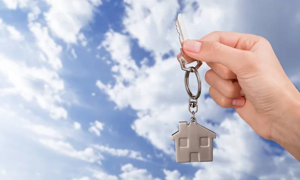 Home key in hand on sky background