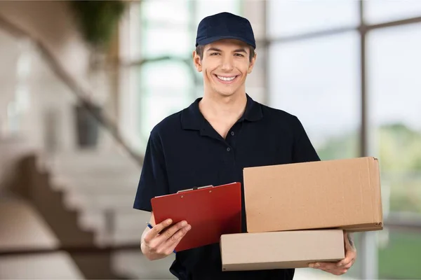 young handsome delivery man with boxes on background