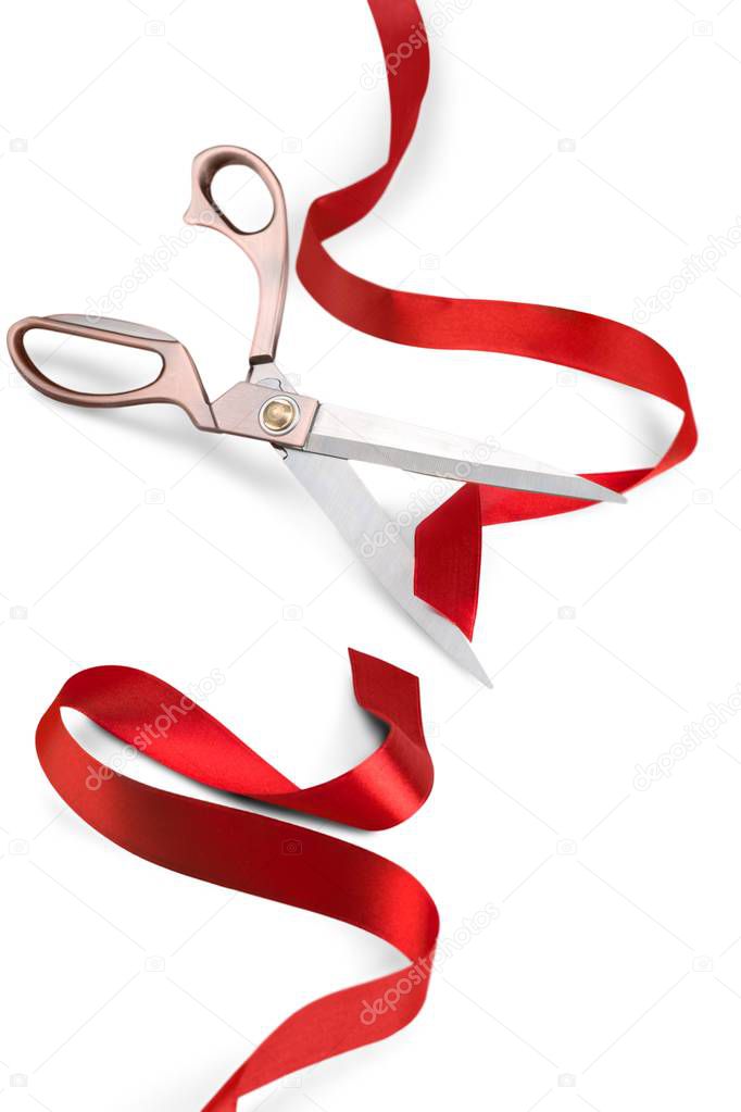 Scissors cutting red ribbon, close-up view on  background