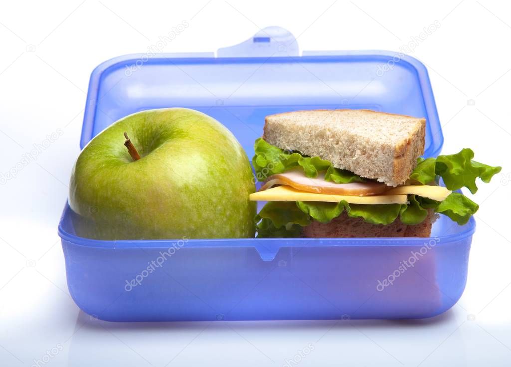 Lunchbox with green apple and sandwich on white background