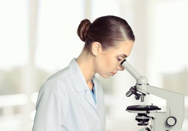 Laboratuvarda mikroskop kullanan genç bir kadın.  