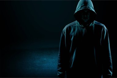 Kapüşonlu bilgisayar korsanı, karanlık arka planda boş siyah kapüşonlu.